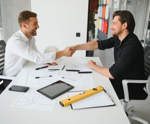 Two colleagues discussing data working on architectural project at construction site at desk in office.